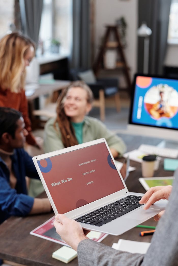 Team discussing project in modern office with laptop displaying presentation.